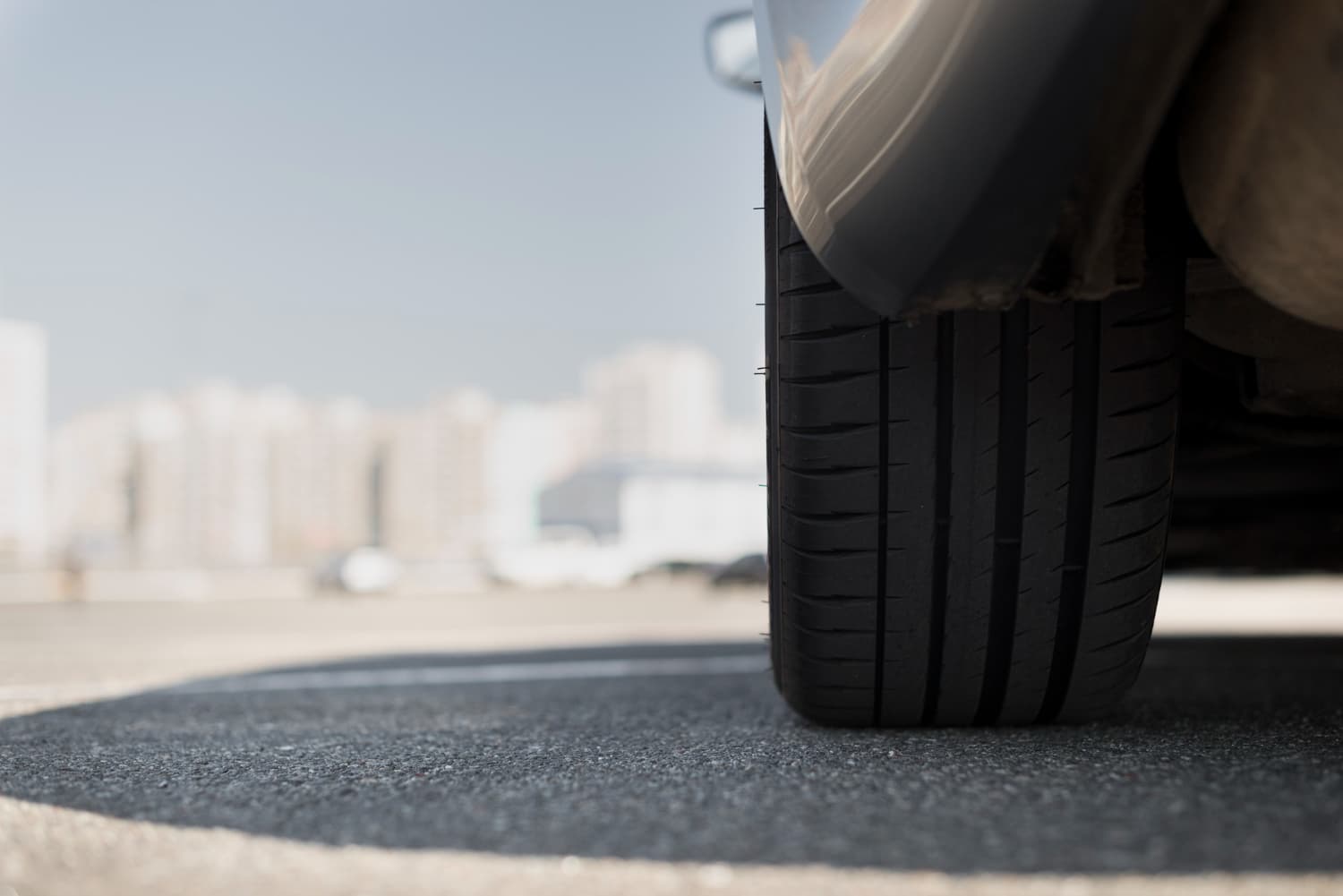 Close-up of a car tire with fresh tread on asphalt in a city parking lot, illustrating safety and road readiness for Iceland campervan rentals.