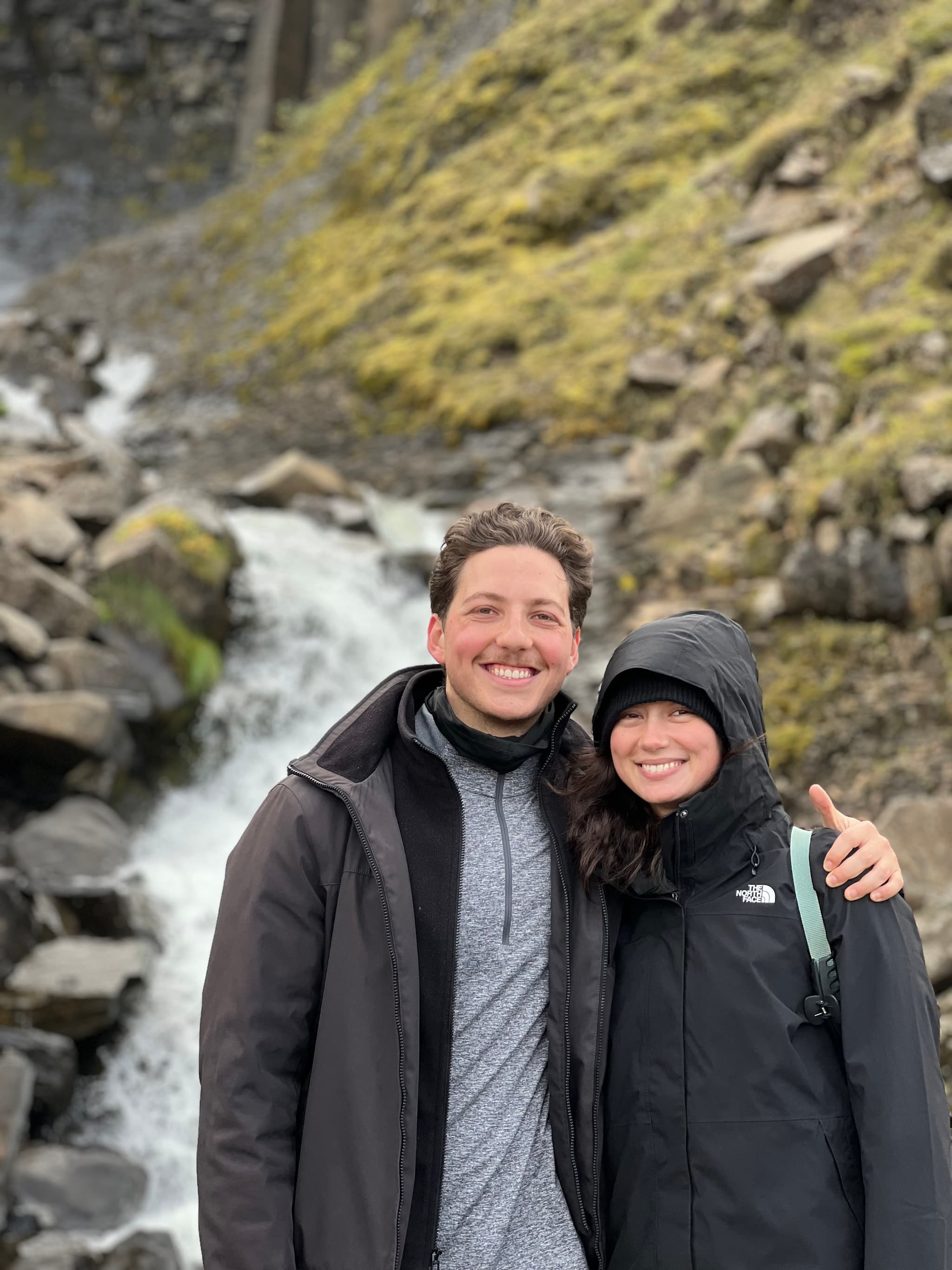 Newlywed couple smiling by a waterfall in Iceland
