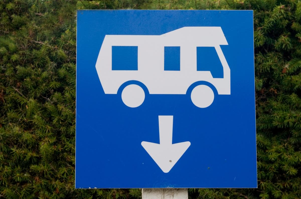 Blue RV dump station sign with a motorhome icon and downward arrow.