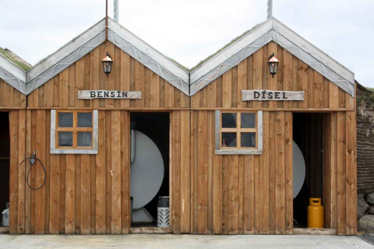 Rustic Icelandic gas station with wooden huts labeled “BENSÍN” and “DÍSEL.”