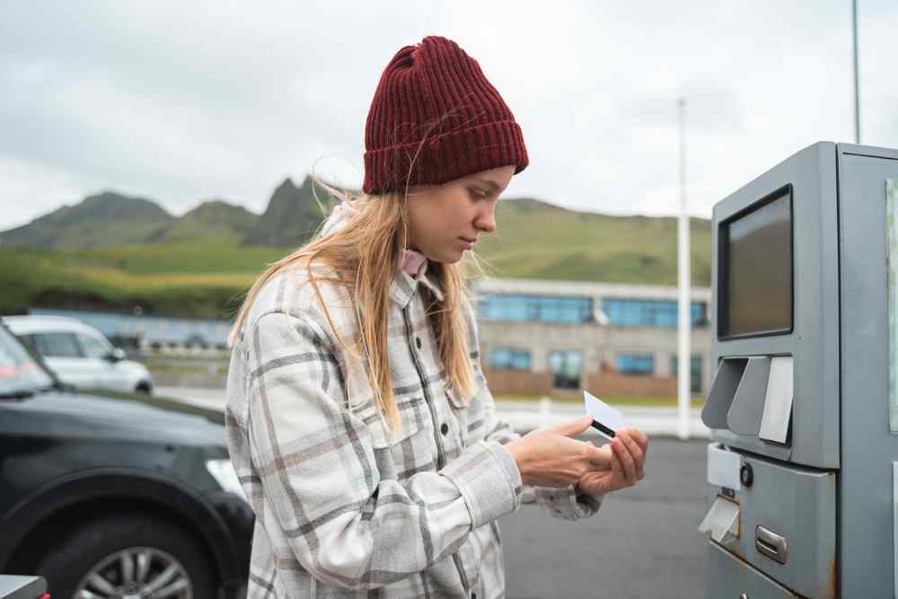 Traveler holding a payment card beside a gas station pump in Iceland.