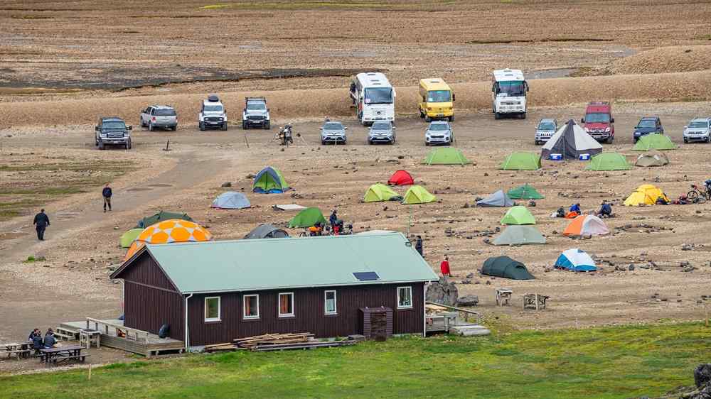 Tents, campervans, and cars at a remote campsite in the Icelandic Highlands.